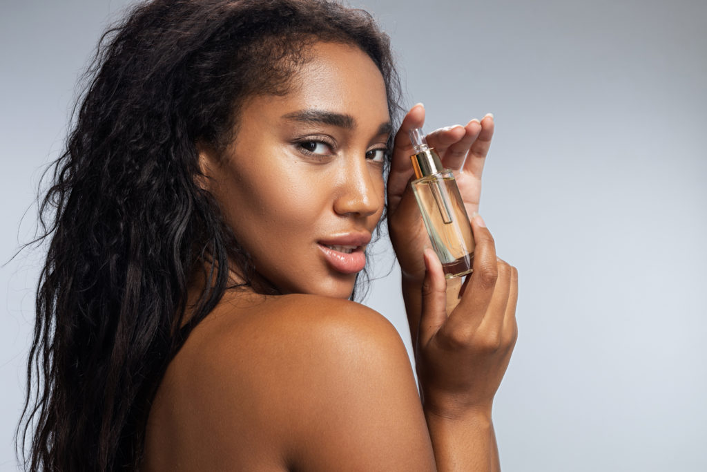 Sexy woman with curly hair keeping bottle with cosmetic liquid. PRF Injections in Houston Texas by The skin Clinic